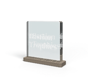 Clear glass engraving with 'Bastion Trophies' engraved on the front, standing on a wooden base.