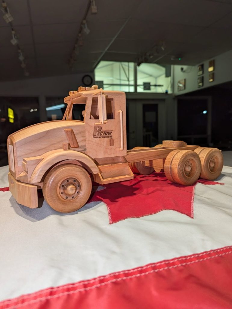 Handmade wooden truck model with laser engraved company logo on the cab door.